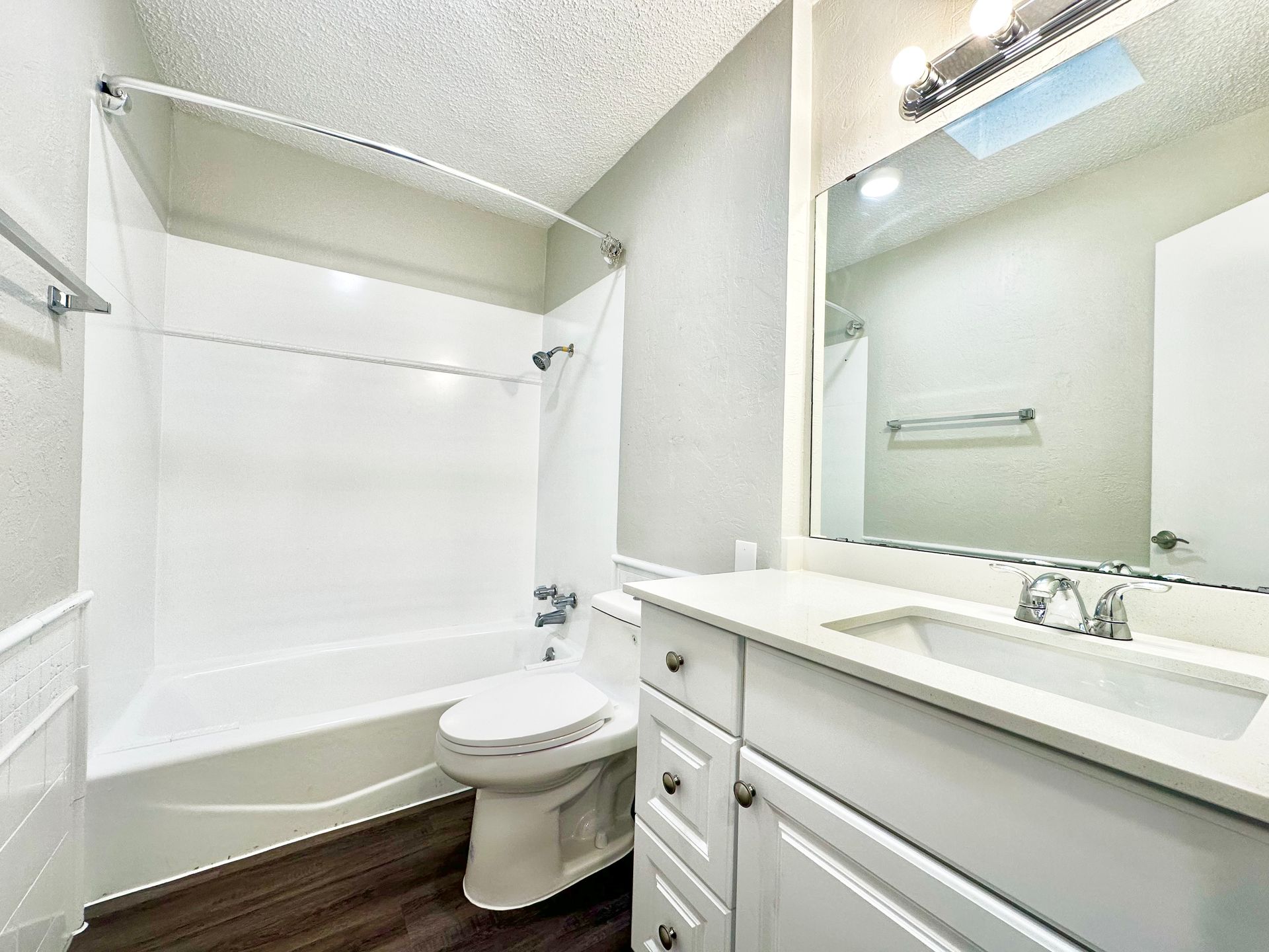 A bathroom with a toilet , sink , tub and mirror.