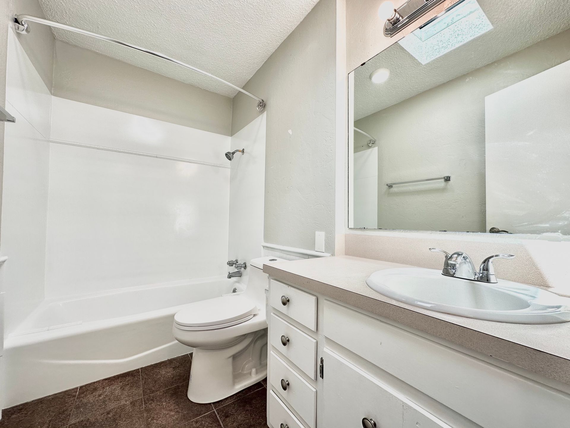 A bathroom with a toilet , sink , bathtub and mirror.