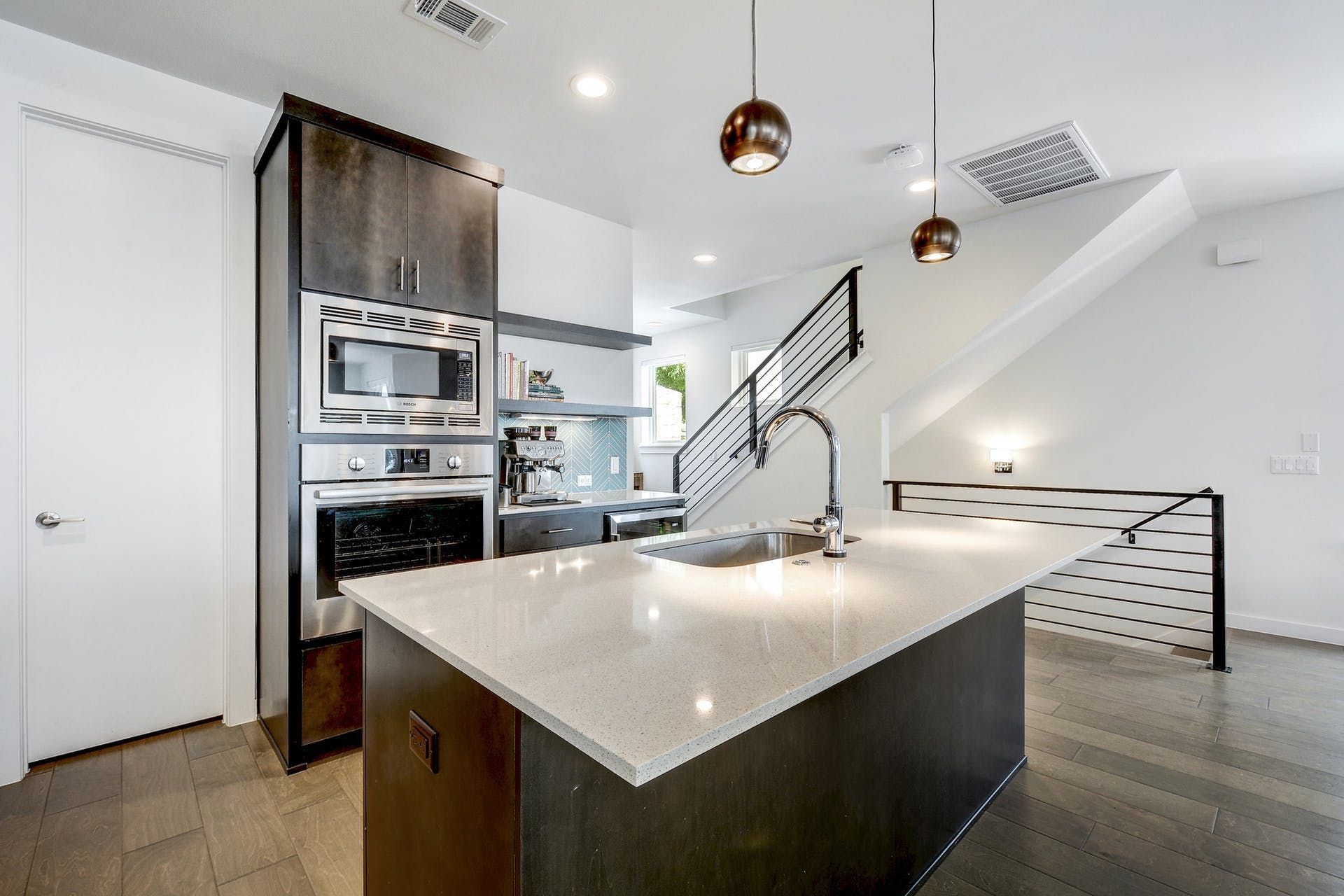 A kitchen with a large island , sink , stove and microwave.