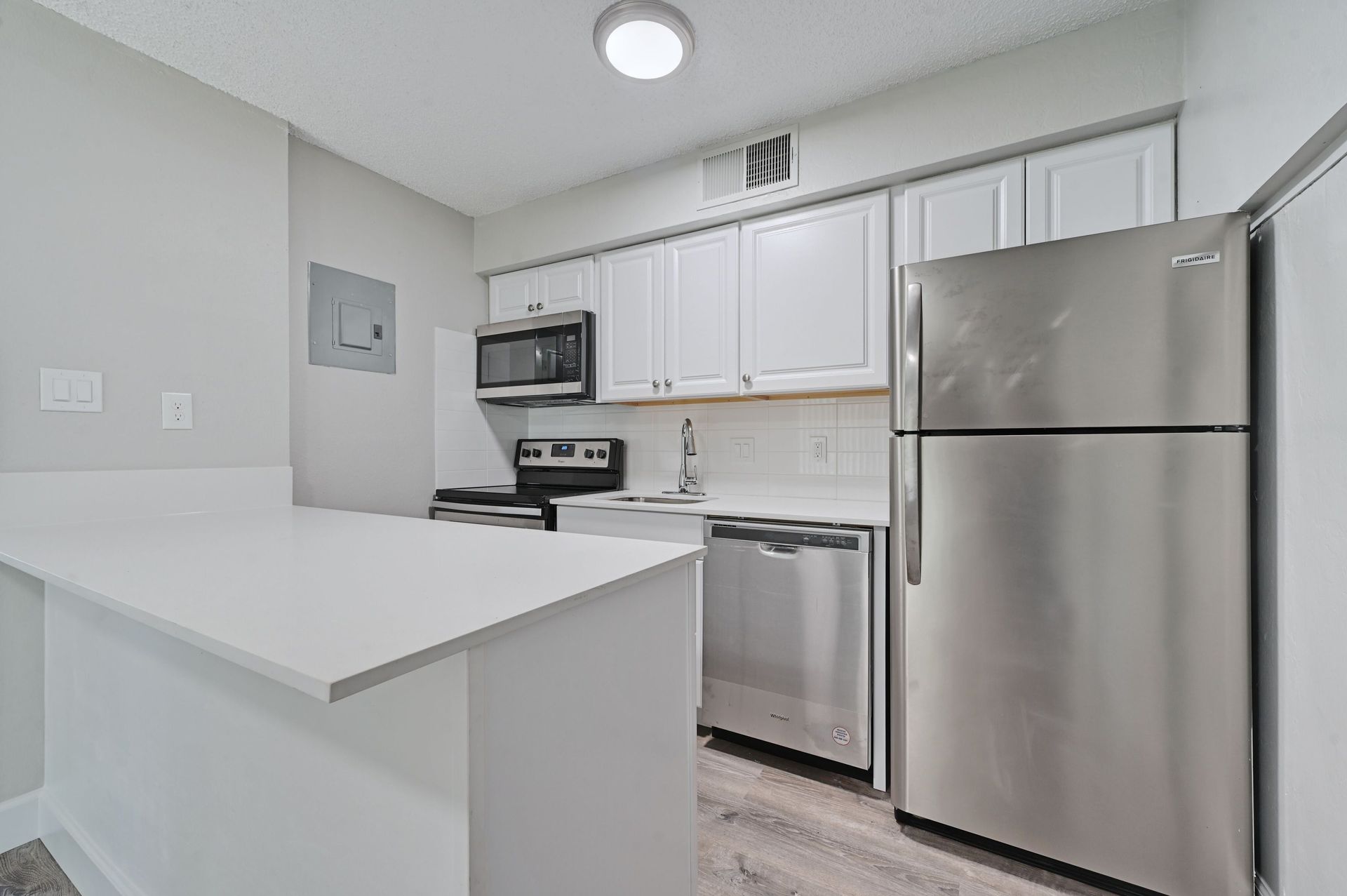 A kitchen with stainless steel appliances and white cabinets.