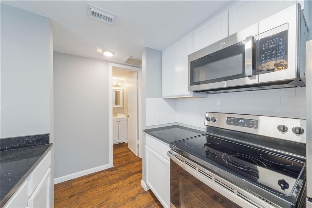 A kitchen with a stove , microwave , and sink.