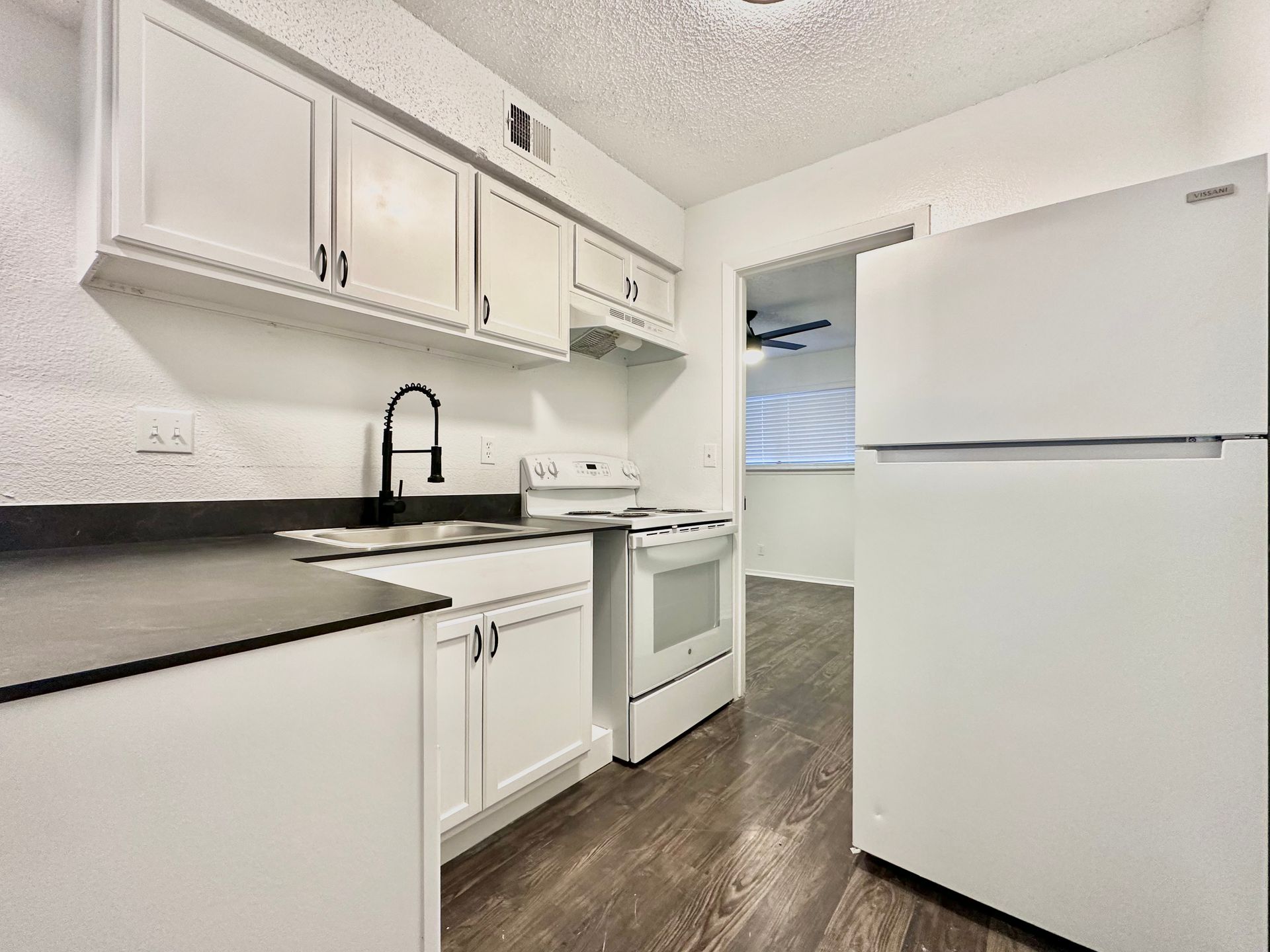 A kitchen with white cabinets , a refrigerator , a stove , and a sink.