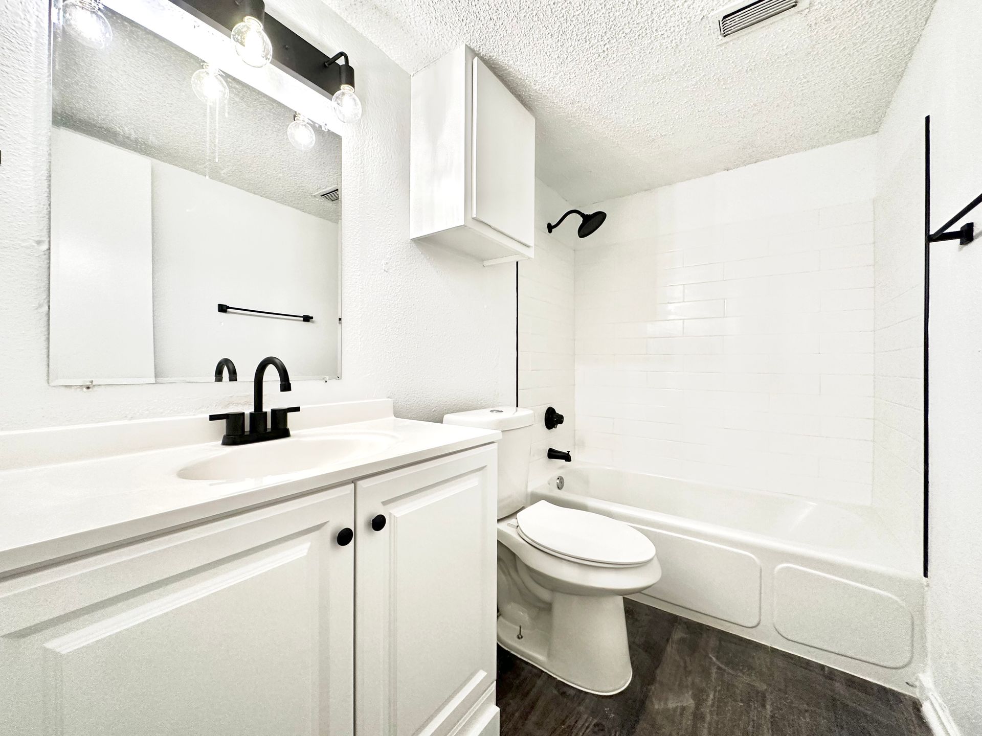 A bathroom with a toilet , sink , mirror and bathtub.
