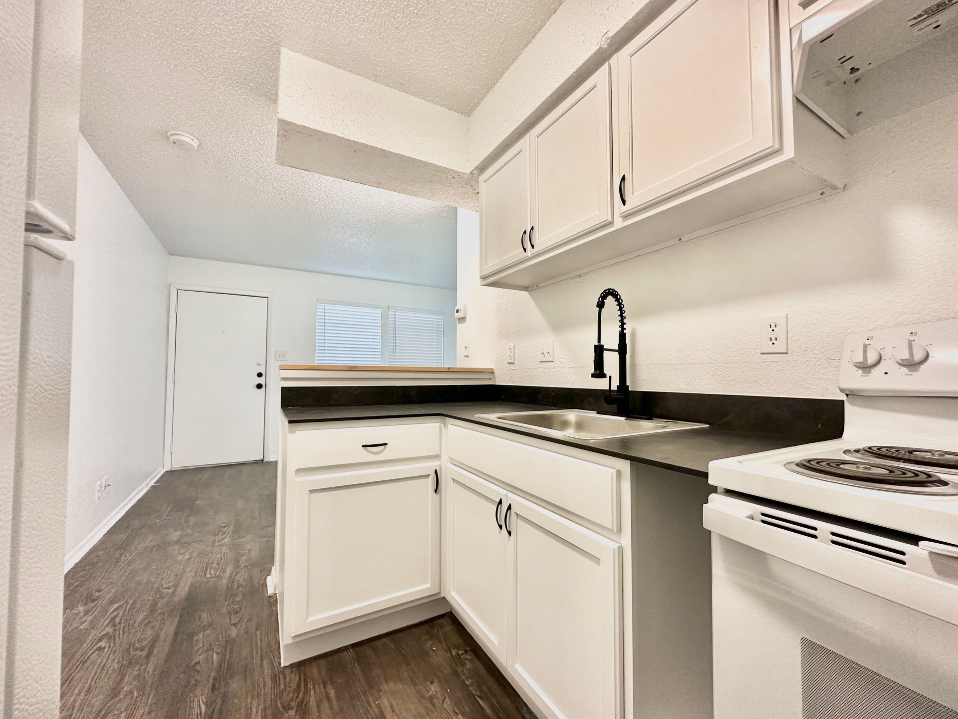 A kitchen with white cabinets , a stove and a sink.