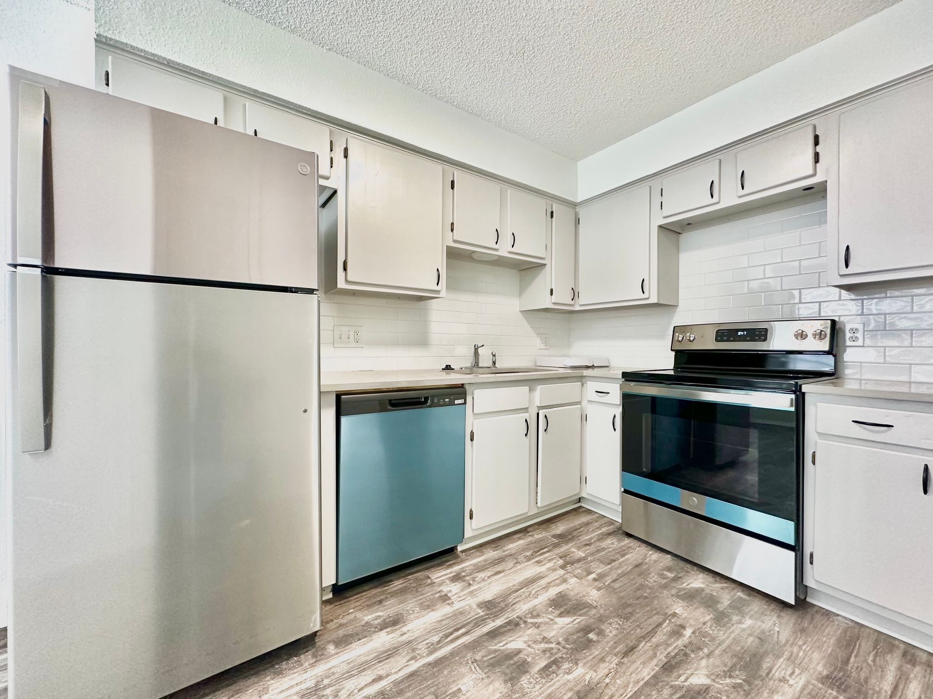 A kitchen with stainless steel appliances and white cabinets.