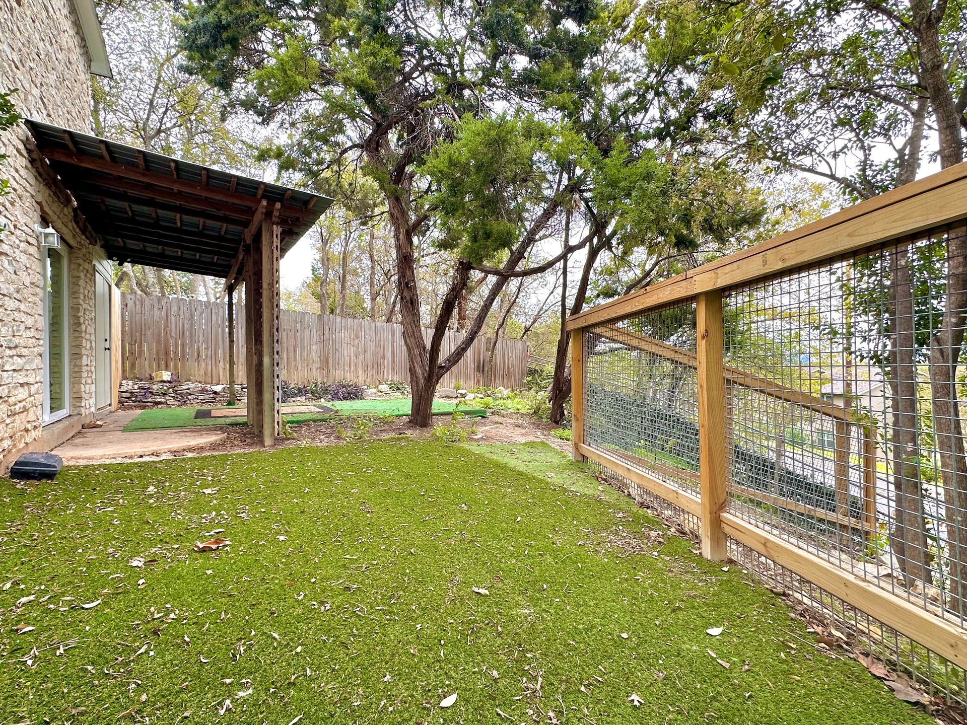 A backyard with a wooden fence and a pergola.