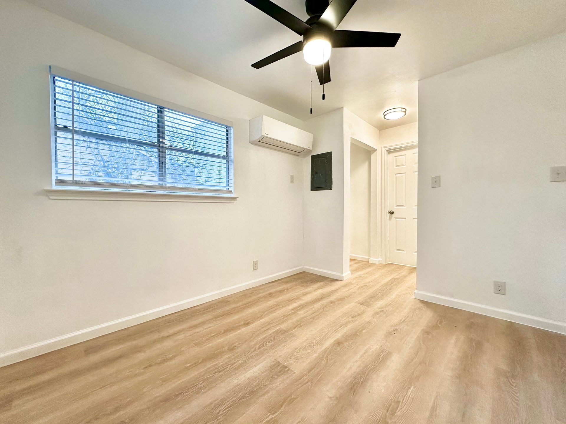 An empty room with a ceiling fan and a window.