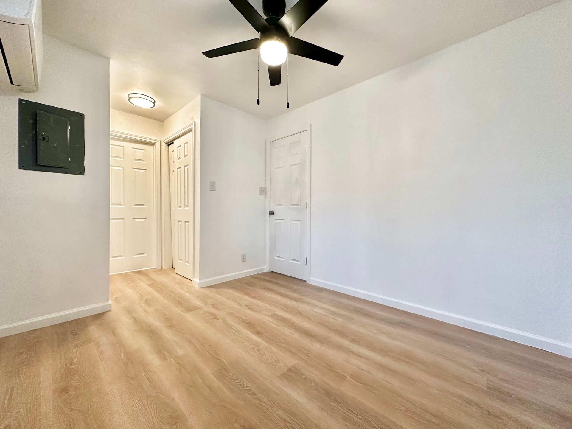 An empty room with hardwood floors and a ceiling fan.