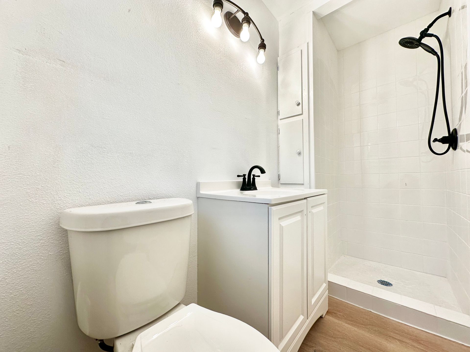 A bathroom with a toilet , sink and shower.