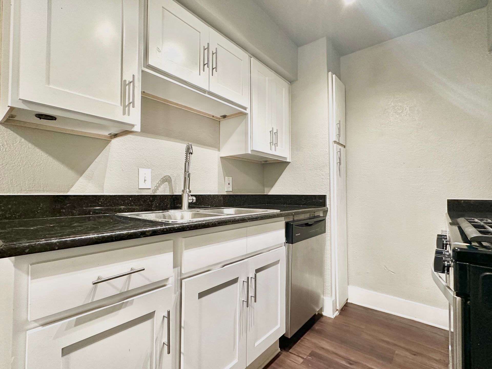 A kitchen with white cabinets , stainless steel appliances , a sink , and a stove.