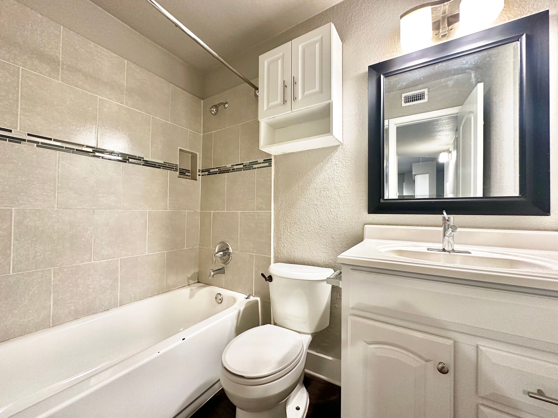 A bathroom with a toilet , sink , bathtub and mirror.
