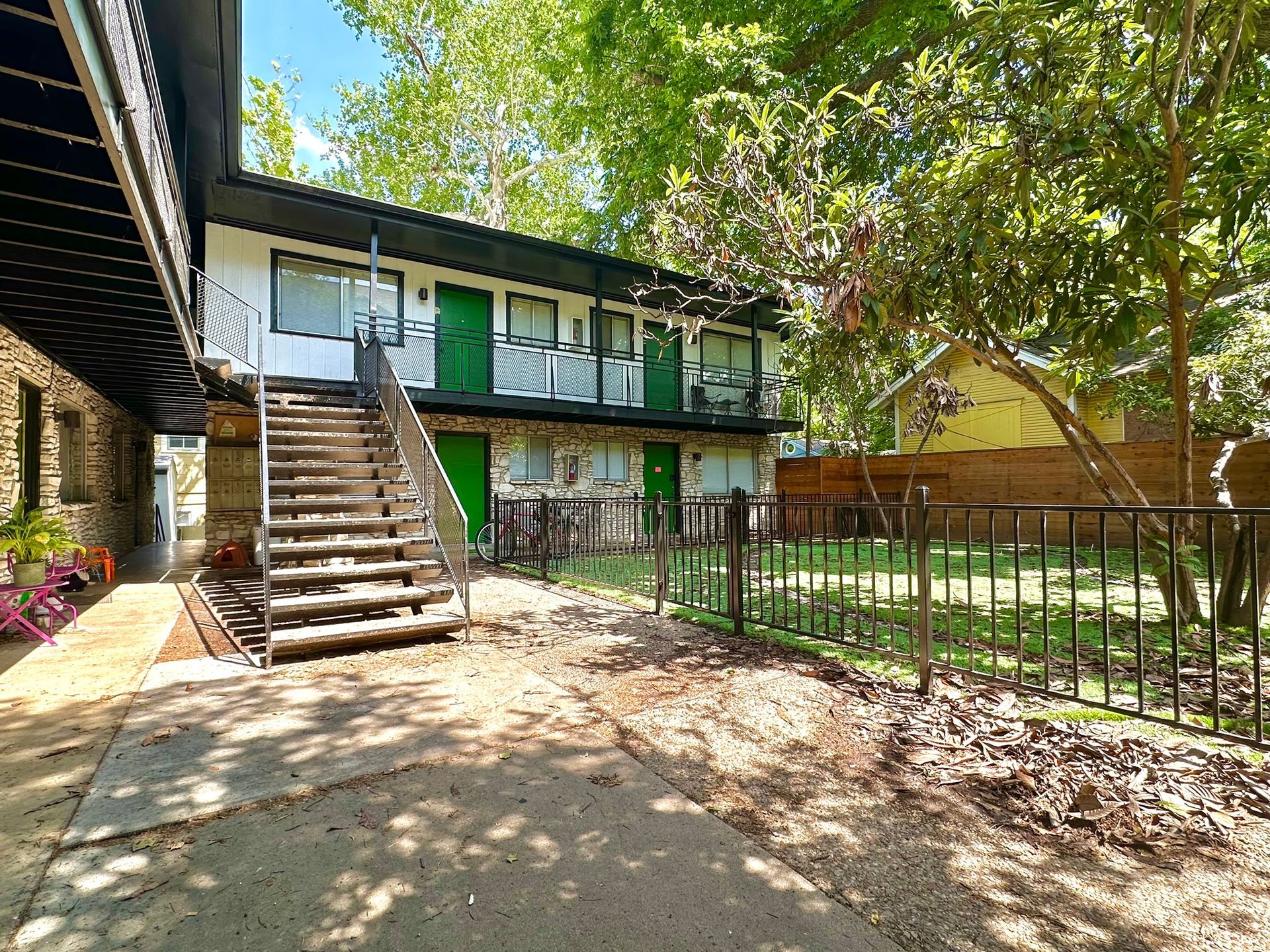 A white and green apartment building with stairs leading up to the second floor.