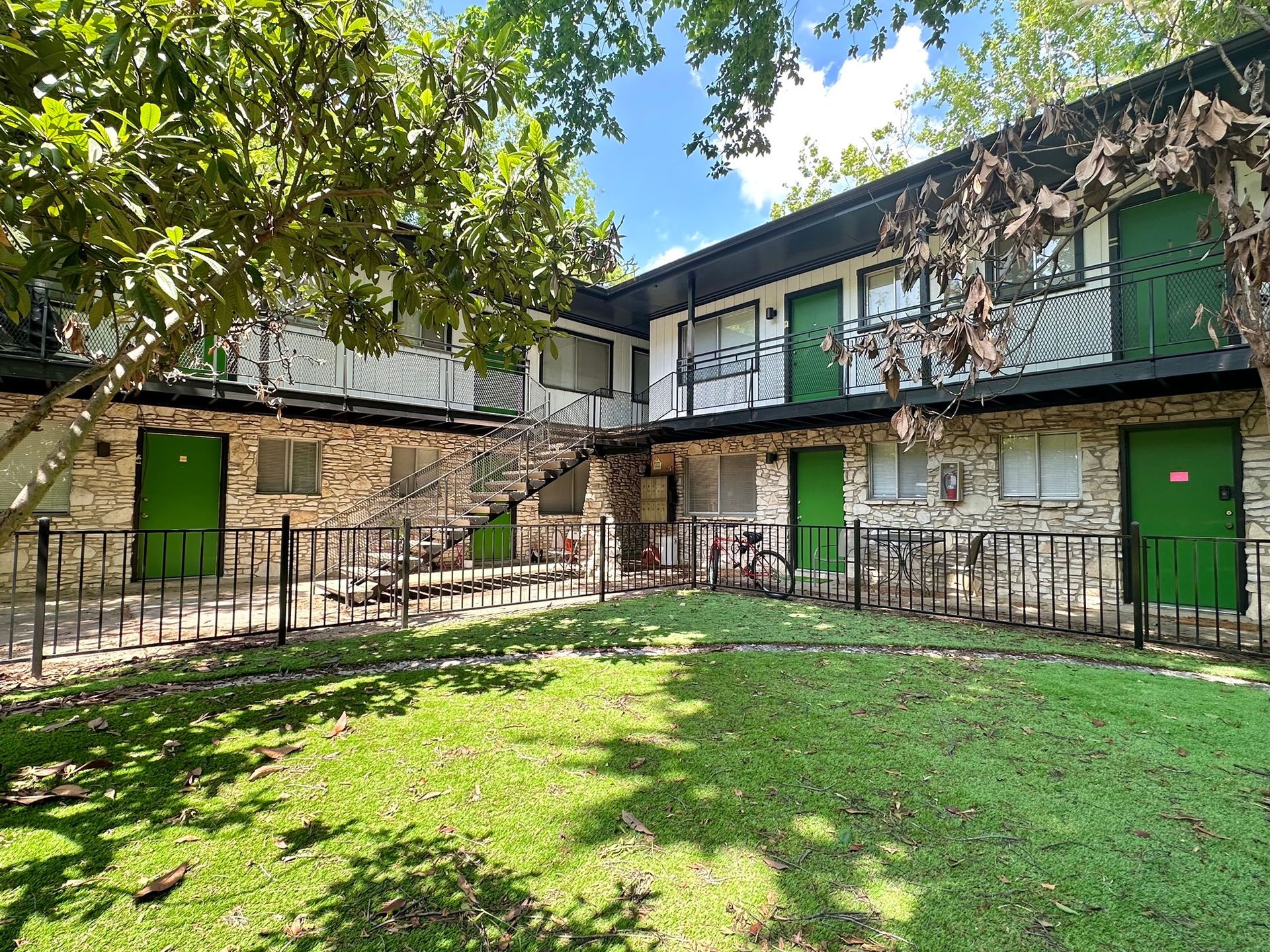 A large apartment building with green doors and a fence around it.