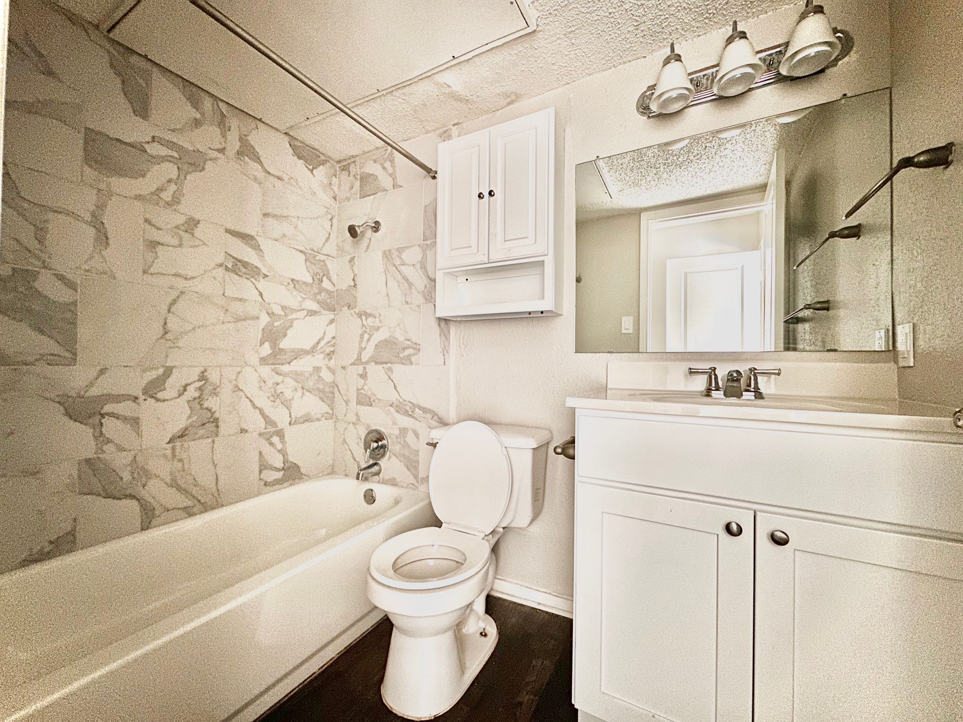 A bathroom with a toilet , sink , bathtub and mirror.