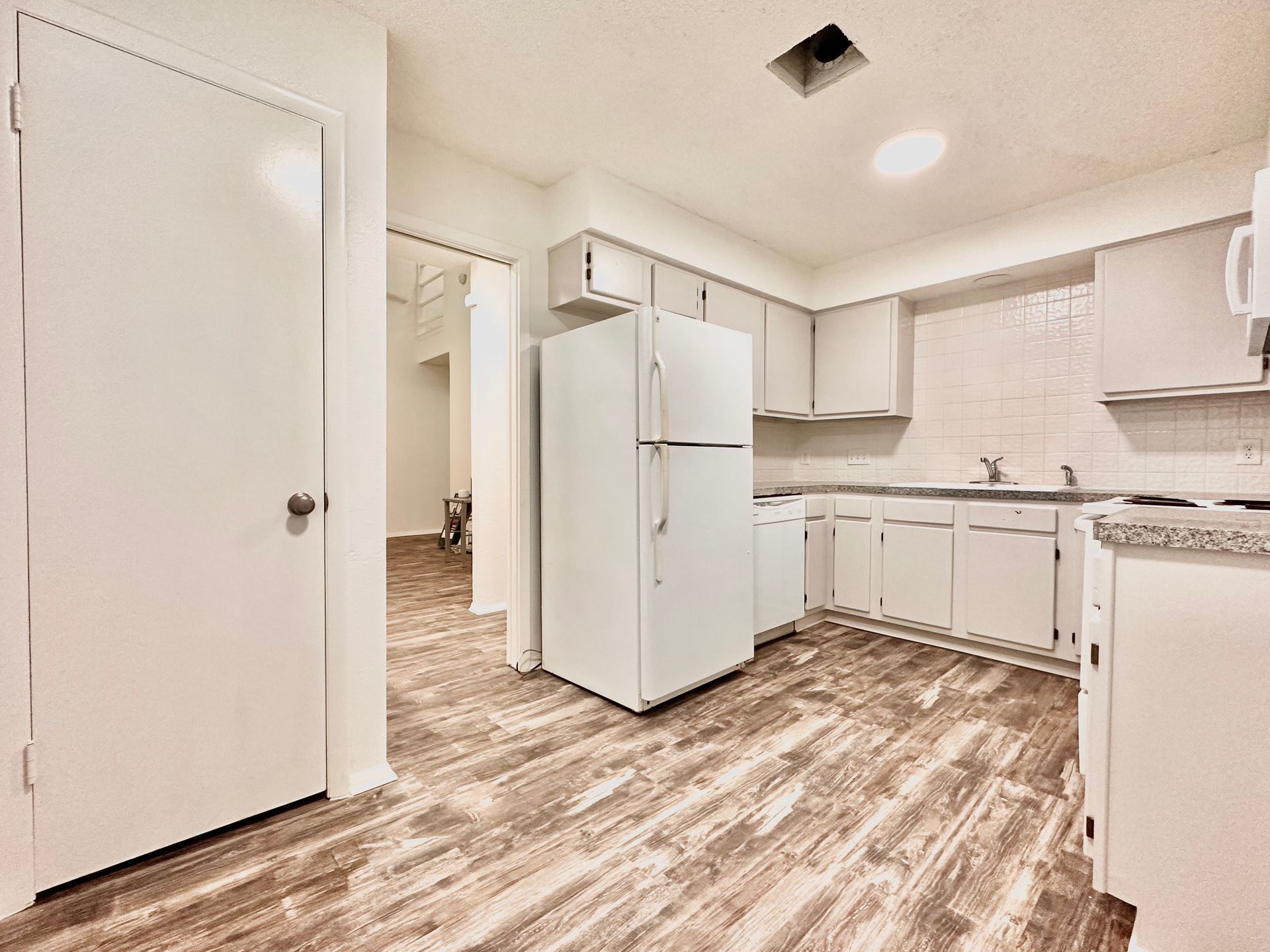 A kitchen with white cabinets and a white refrigerator.