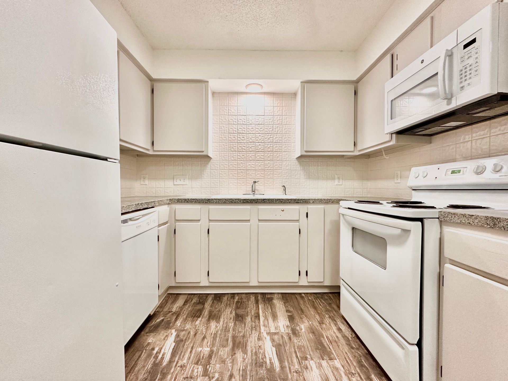 A kitchen with a refrigerator , stove , microwave and sink.