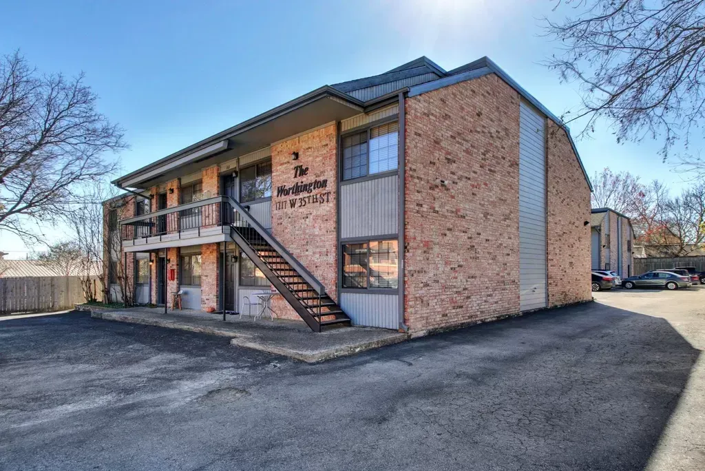 A brick apartment building with stairs leading up to the second floor.