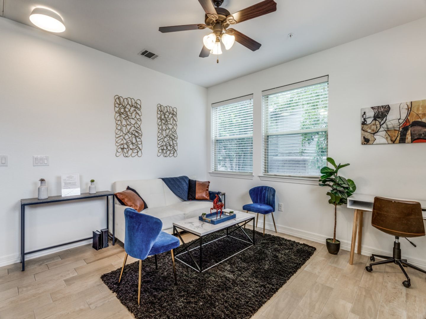 A living room with a couch , chairs , table and ceiling fan.