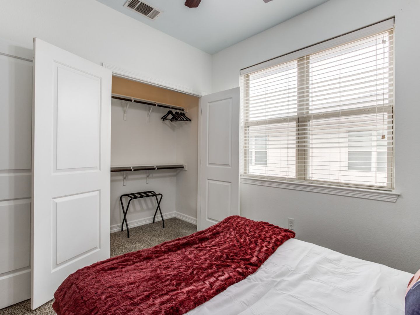 A bedroom with a bed , closet and window.