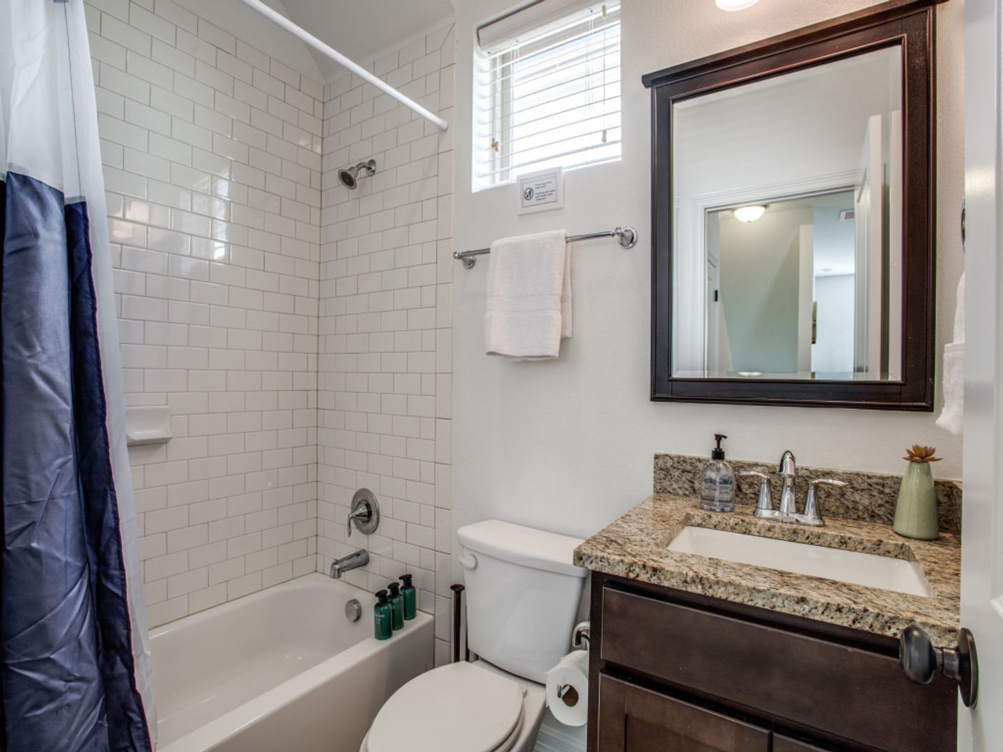A bathroom with a toilet , sink , tub and mirror.
