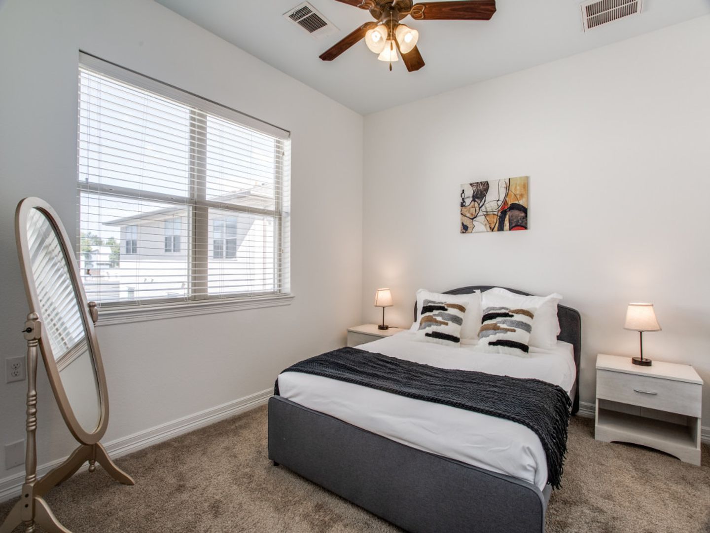 A bedroom with a bed , nightstand , mirror and ceiling fan.
