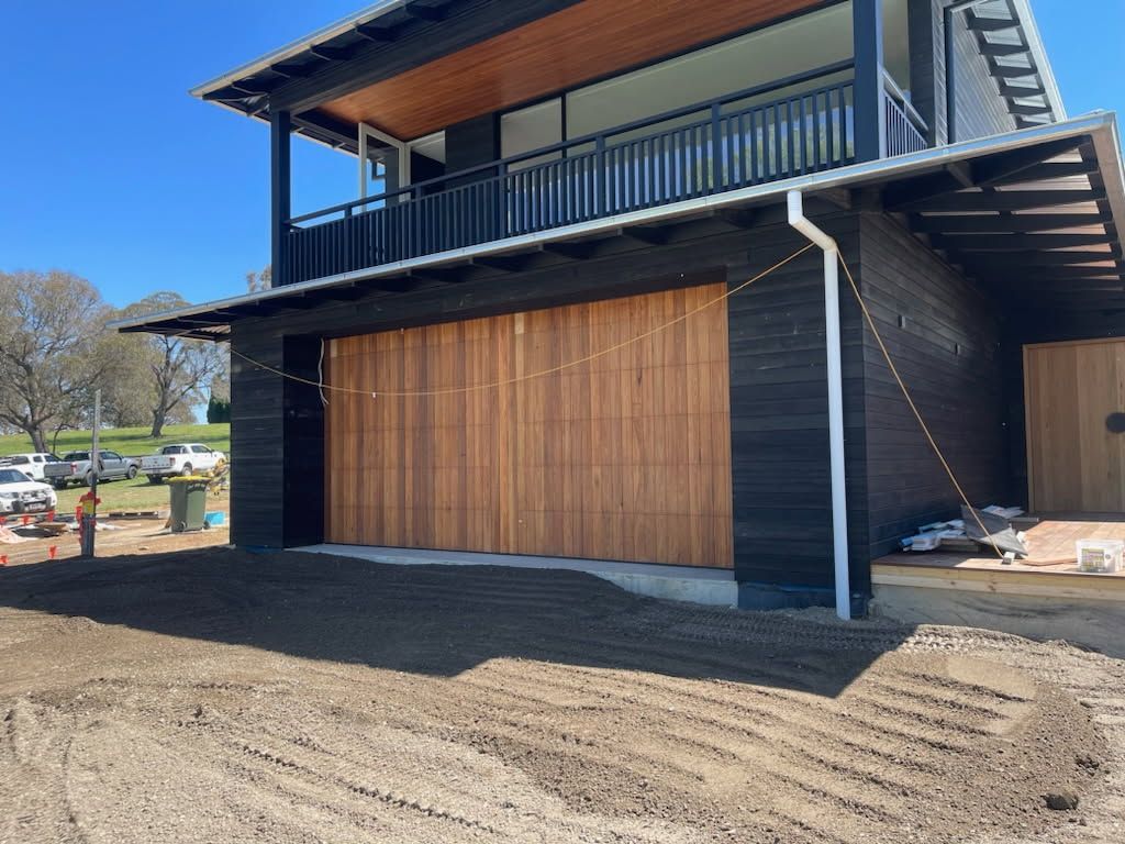 A Man is Working on a Garage Door With a Wrench — Schofield's Garage Doors in Robertson, NSW