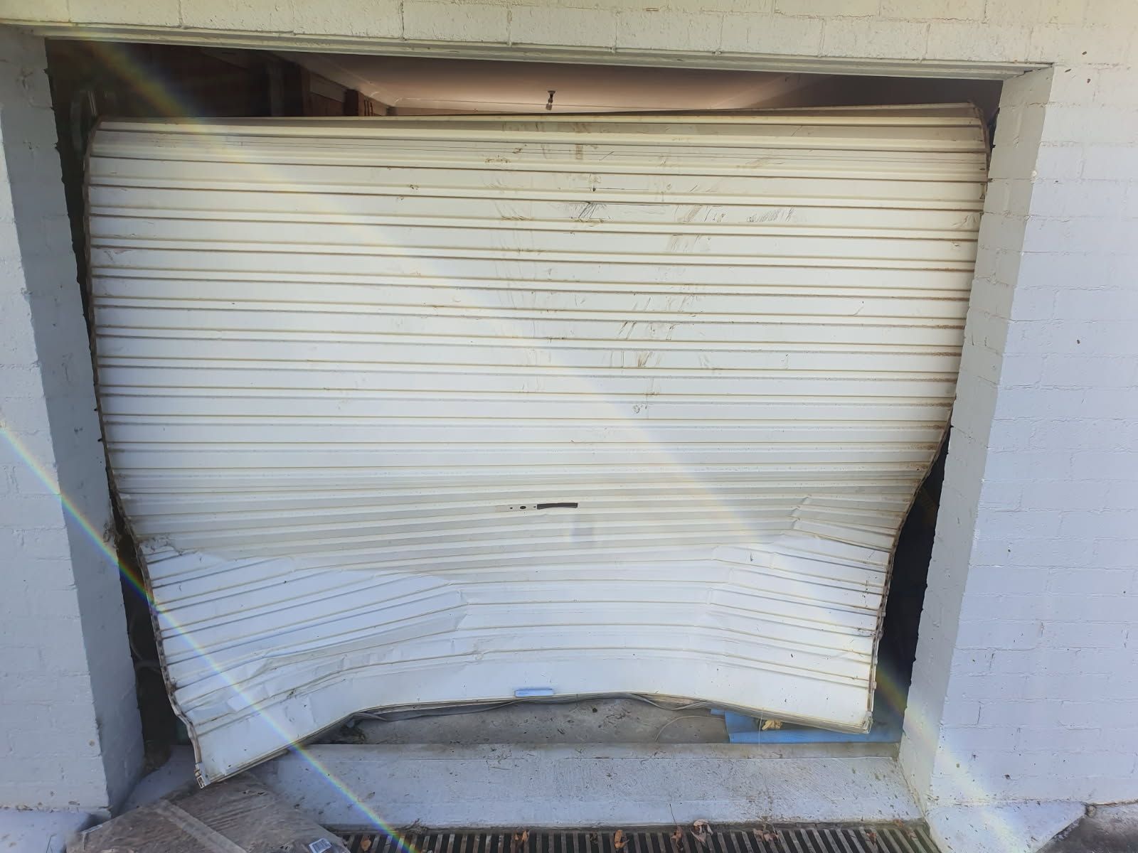 A White Garage Door That Has Been Broken in Half — Schofield's Garage Doors in Robertson, NSW