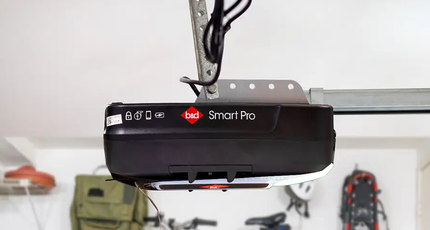A Black Garage Door Opener is Hanging From the Ceiling in a Garage — Schofield's Garage Doors in Robertson, NSW