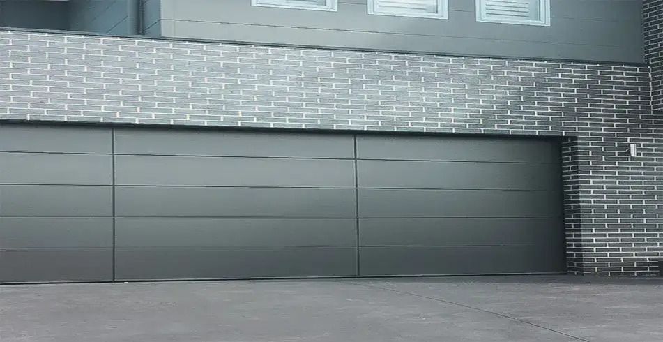 A Large Gray Garage Door is Sitting in Front of a Brick Building — Schofield's Garage Doors in Robertson, NSW