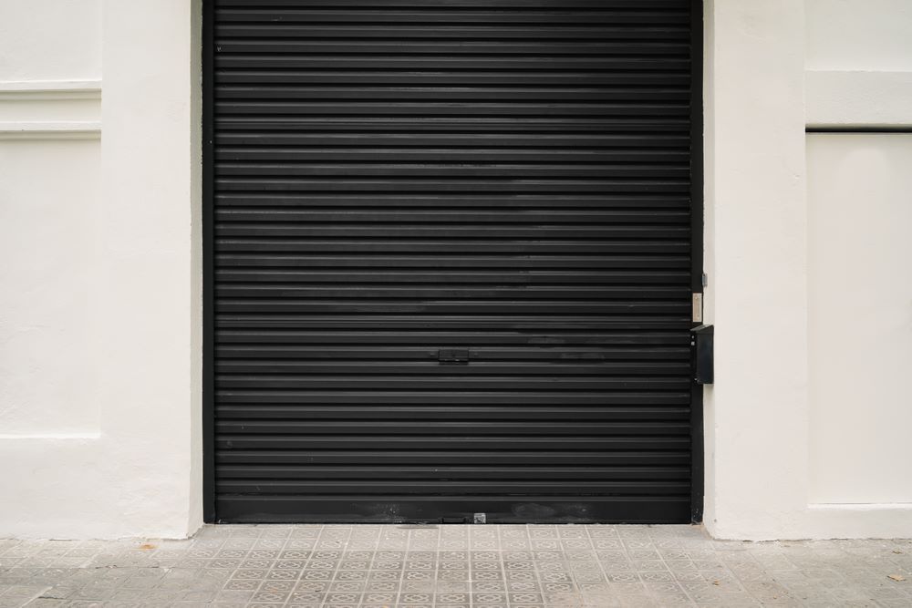 A Black Garage Door is Closed on a White Building — Schofield's Garage Doors in Robertson, NSW