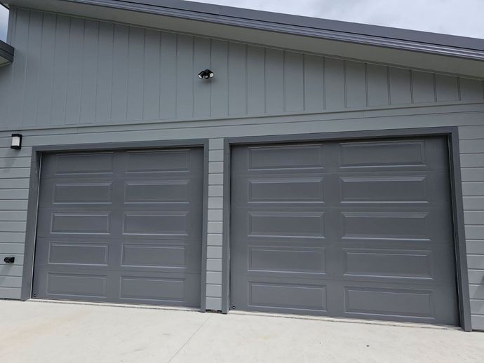 A Wooden Garage Door is Sitting on the Side of a Building — Schofield's Garage Doors in Robertson, NSW