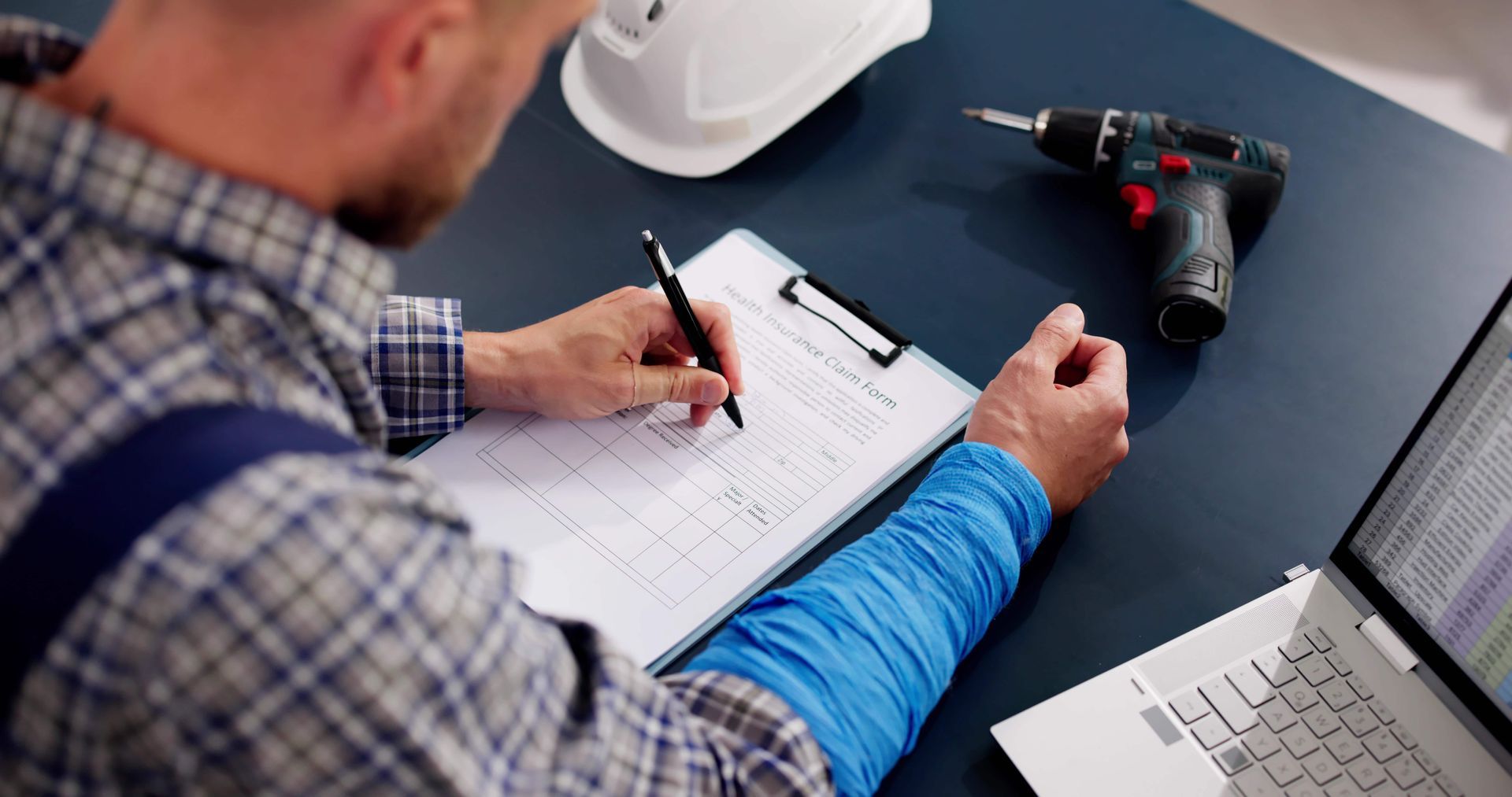 A man is sitting at a desk writing on a clipboard.