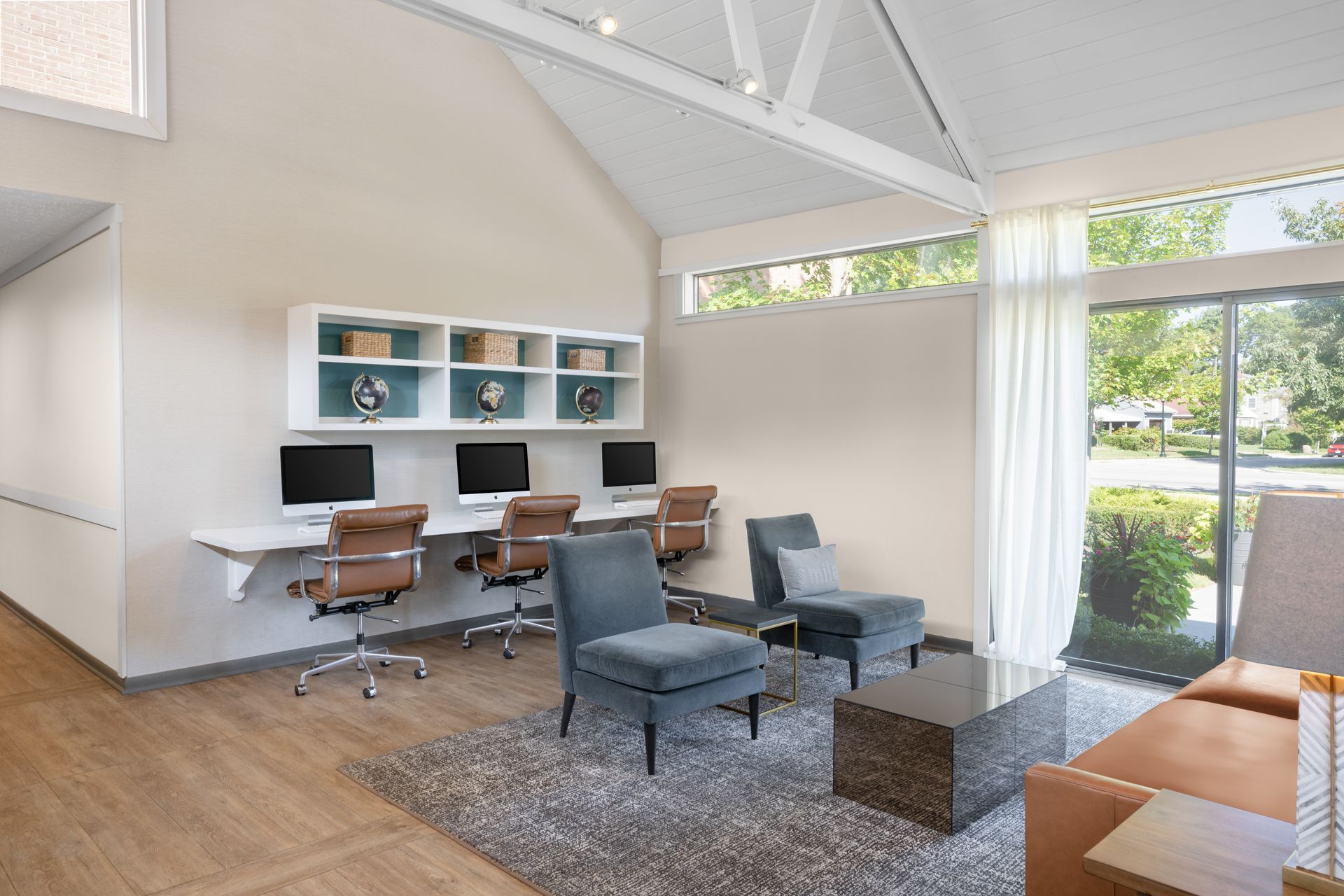 A living room with a couch , chairs , desks and computers.