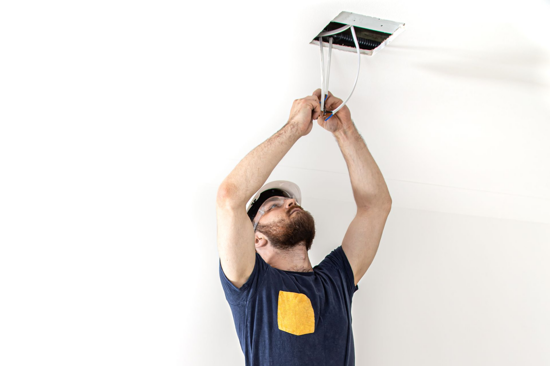Person installing electrical wiring in a white ceiling; using hands to work.