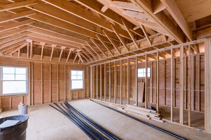 Interior of a room under construction, with wooden framing, windows, and exposed beams.