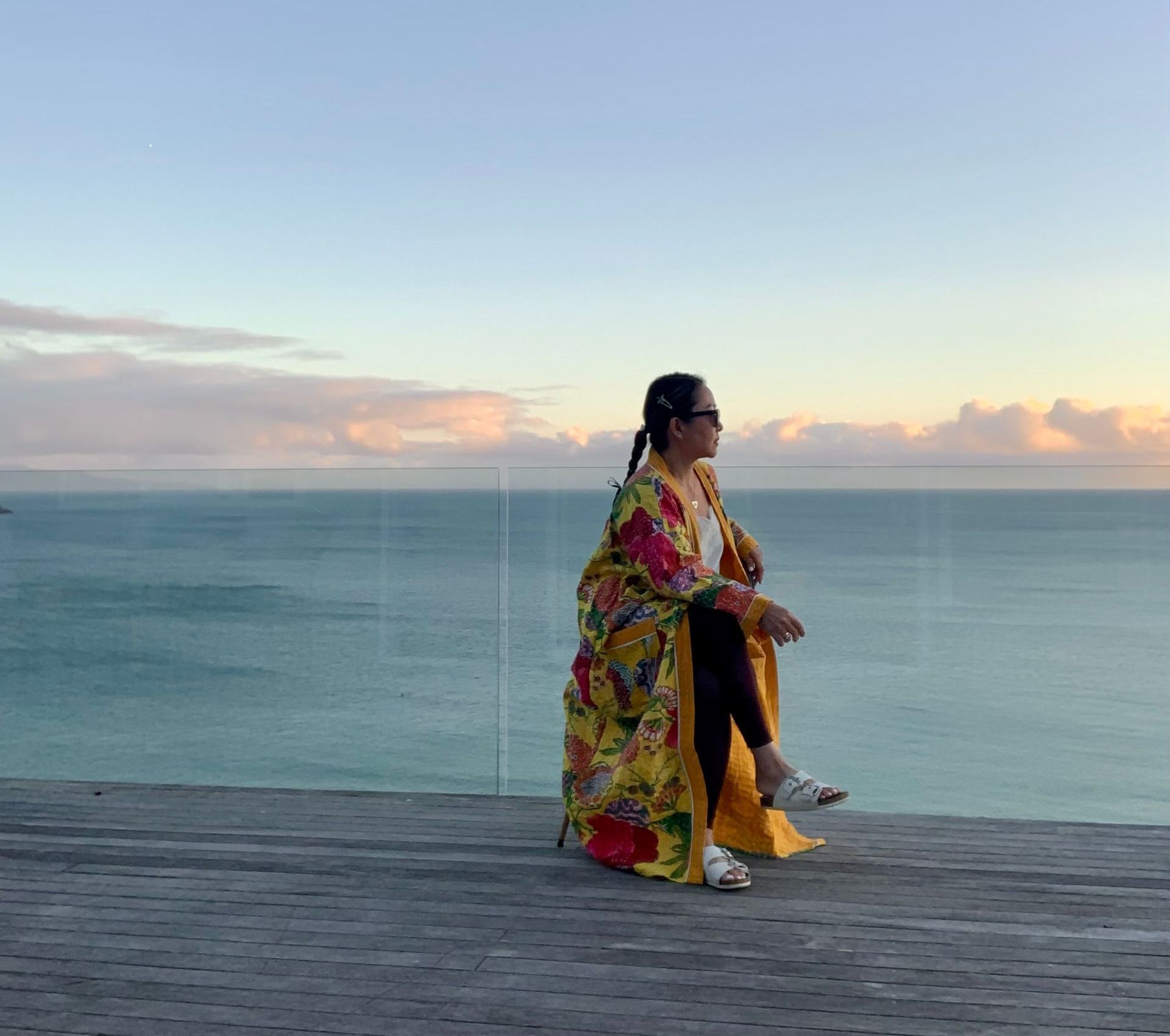 A woman is thinking whilst overlooking an ocean cliff