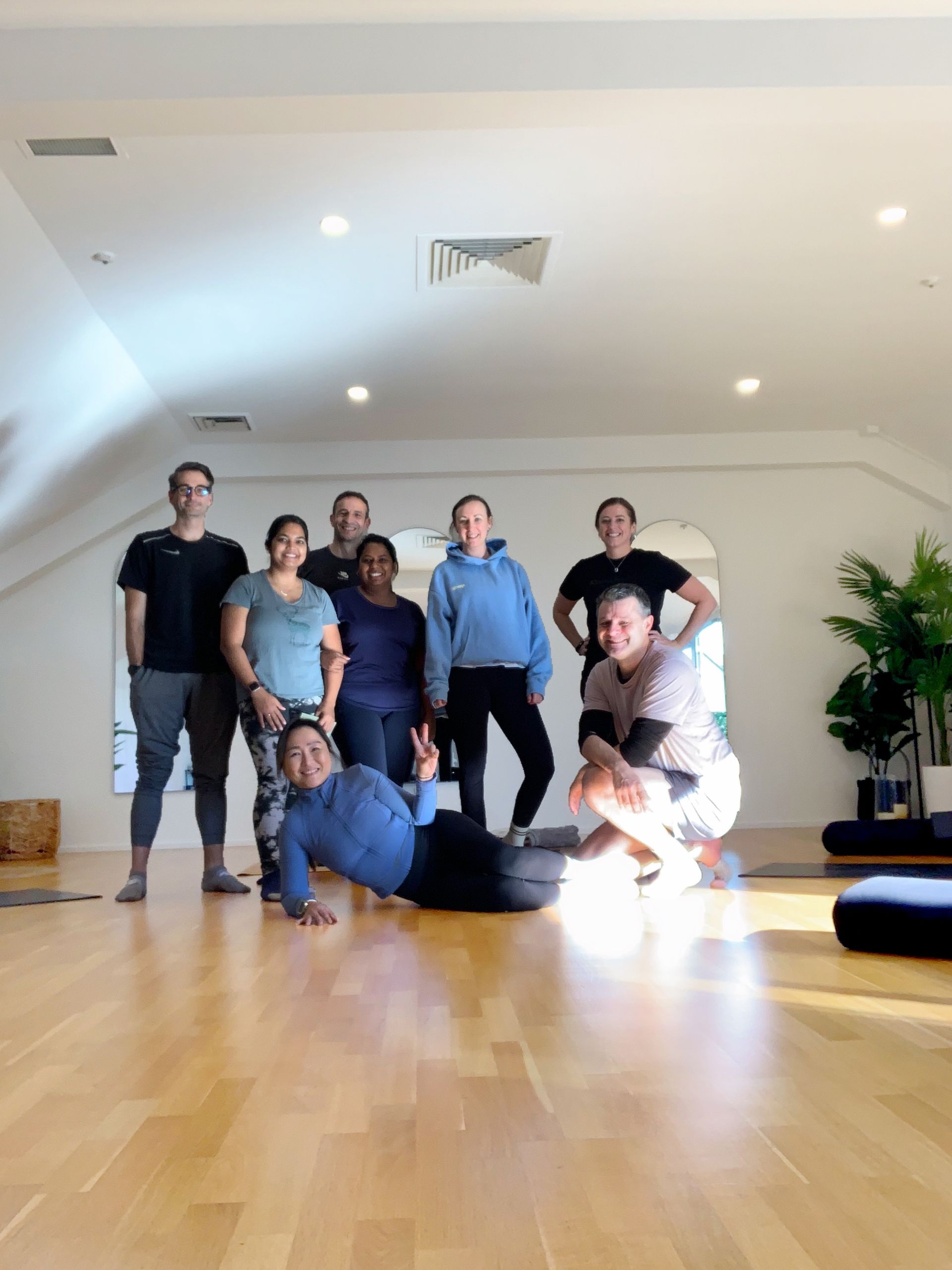 A group of people are posing for a picture in a yoga studio.