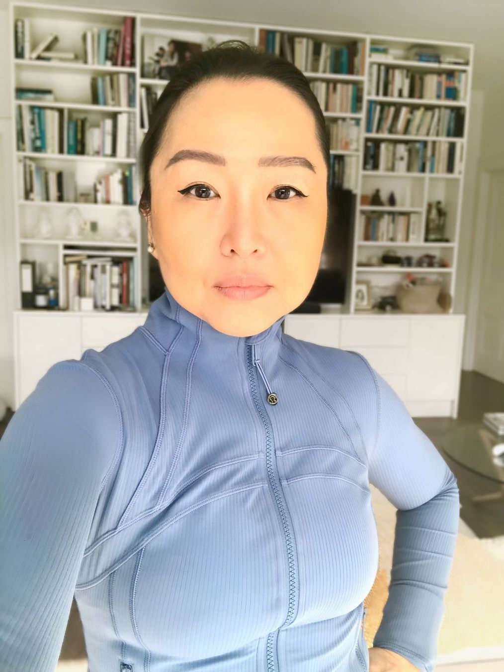 A woman taking a selfie in front of a bookshelf