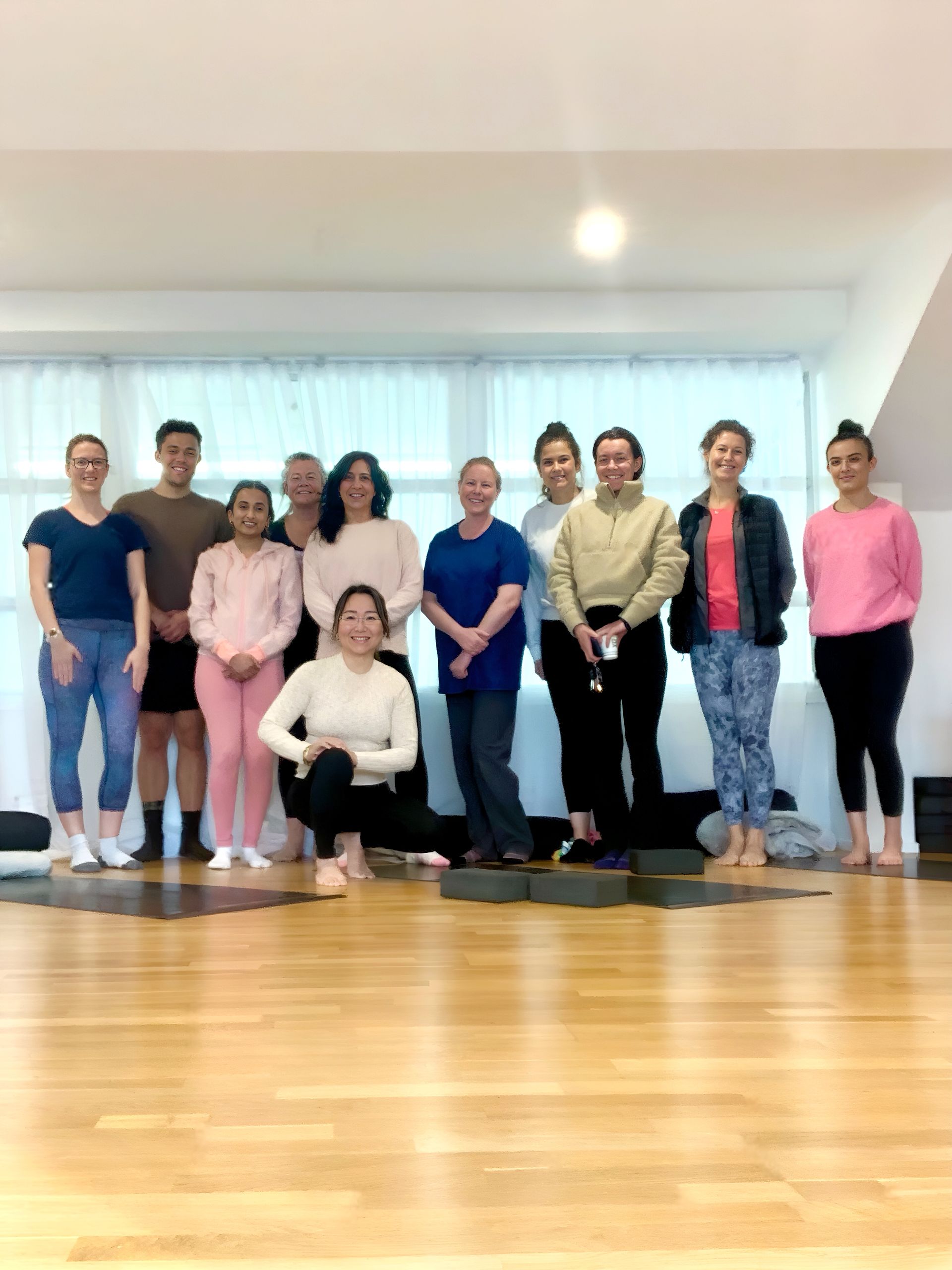 A group of people are posing for a picture in a yoga studio.