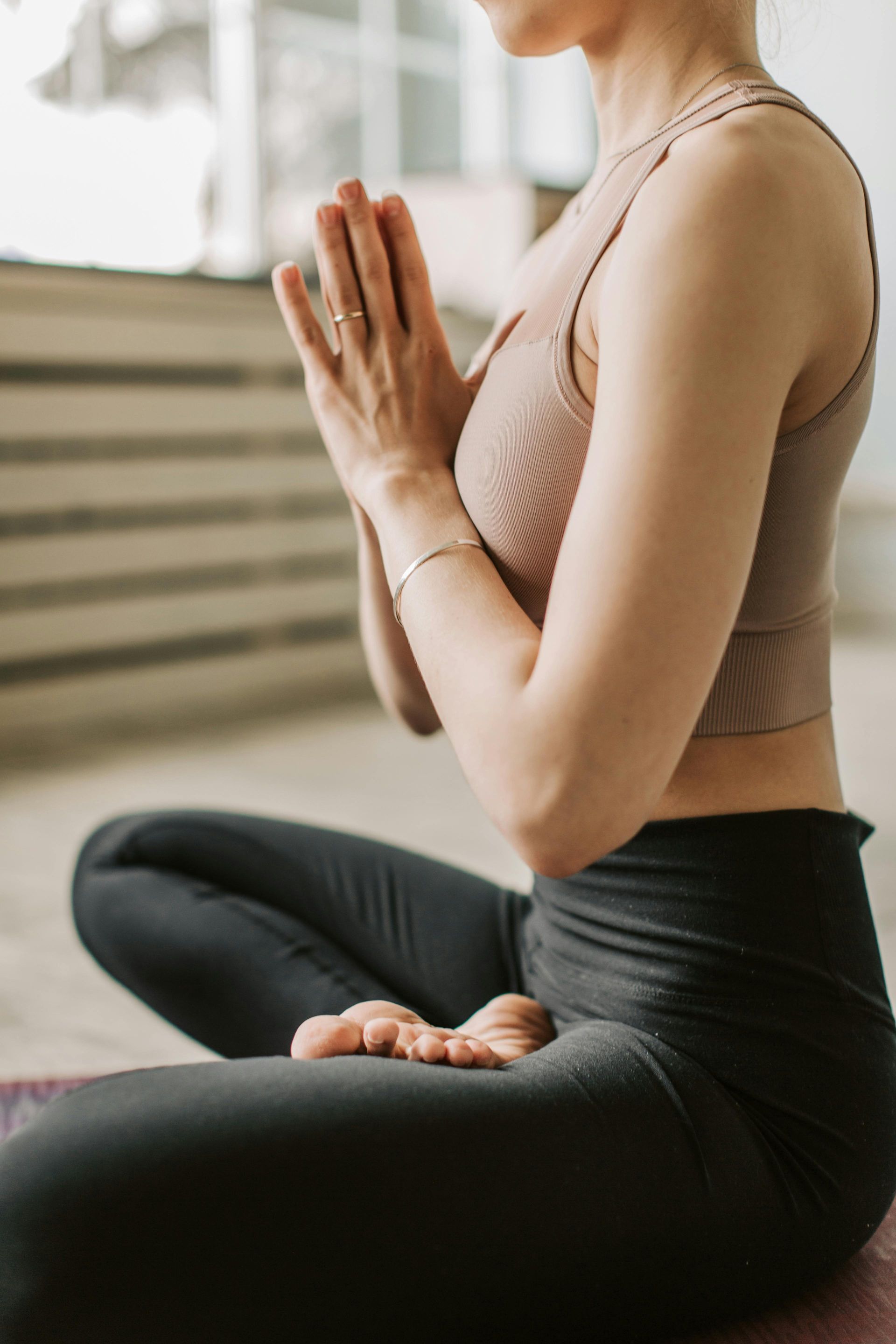 A woman is sitting in a lotus position with her hands folded in prayer.