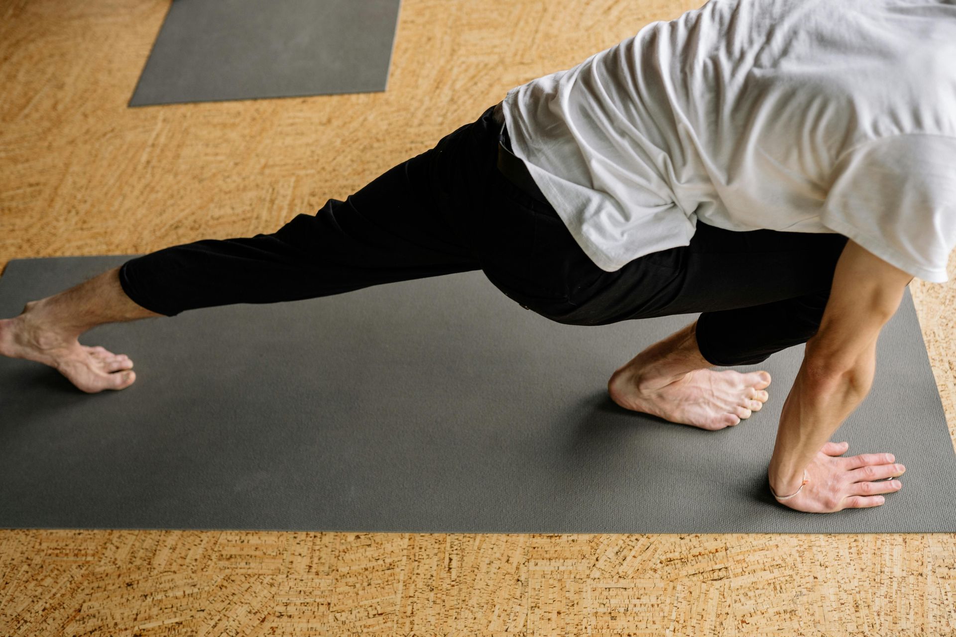 Person in black activewear performing upward-facing dog yoga pose on a mat against a dark background.