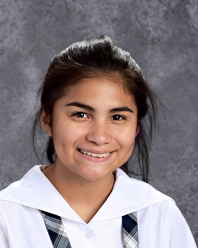 A young girl in a school uniform is smiling for the camera