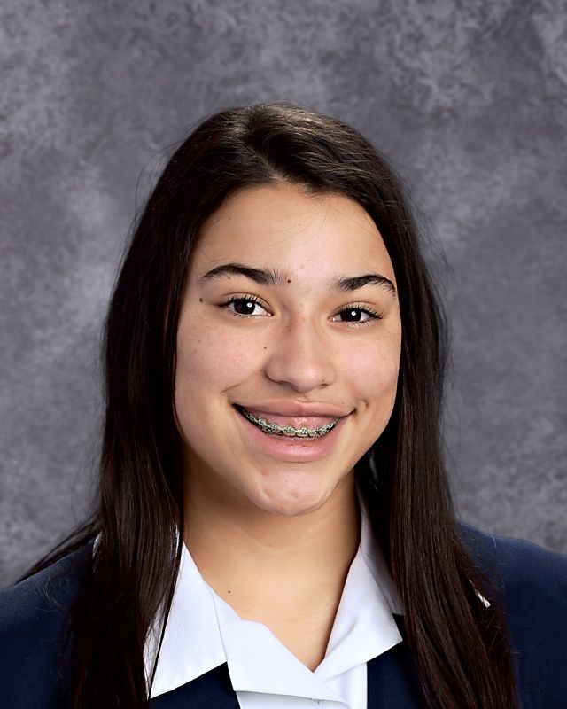 A girl with braces on her teeth is smiling for the camera