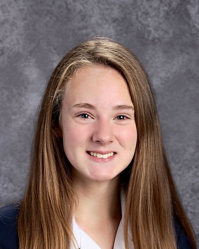 A young girl with long brown hair is smiling for the camera.