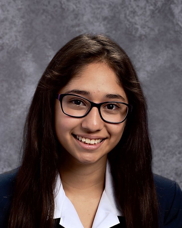 A young woman wearing glasses and a white shirt smiles for the camera