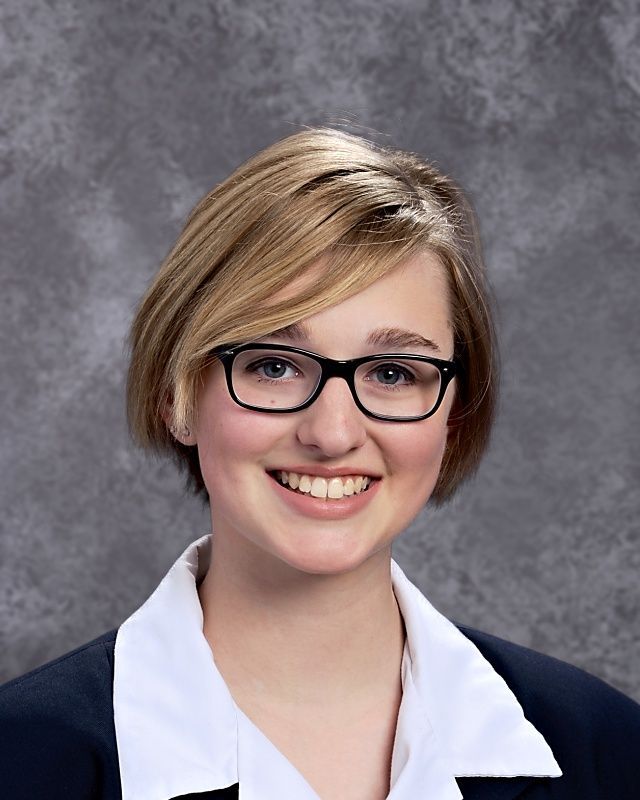 A young woman wearing glasses and a white shirt smiles for the camera