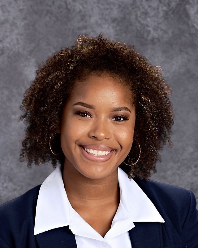 A young woman with curly hair is smiling for the camera