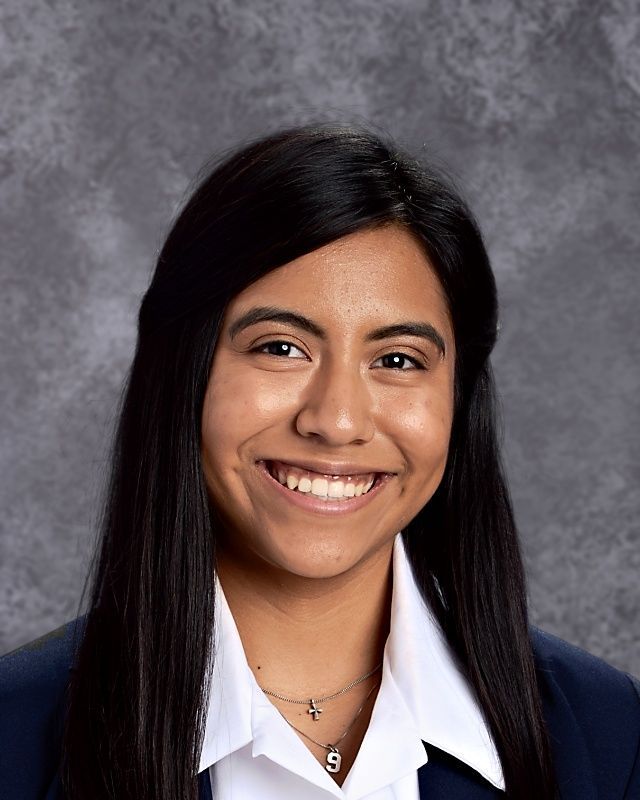 A woman in a blue jacket and white shirt is smiling for the camera.