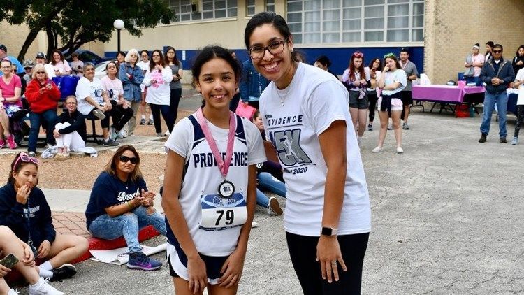 A woman is standing next to a young girl wearing a medal.