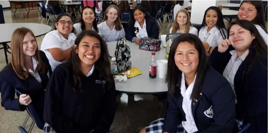 a group of girls in school uniforms are sitting around a table